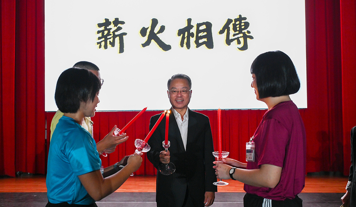 校長向3名115年新生代表傳遞薪傳之火，象徵警大精神綿延不盡